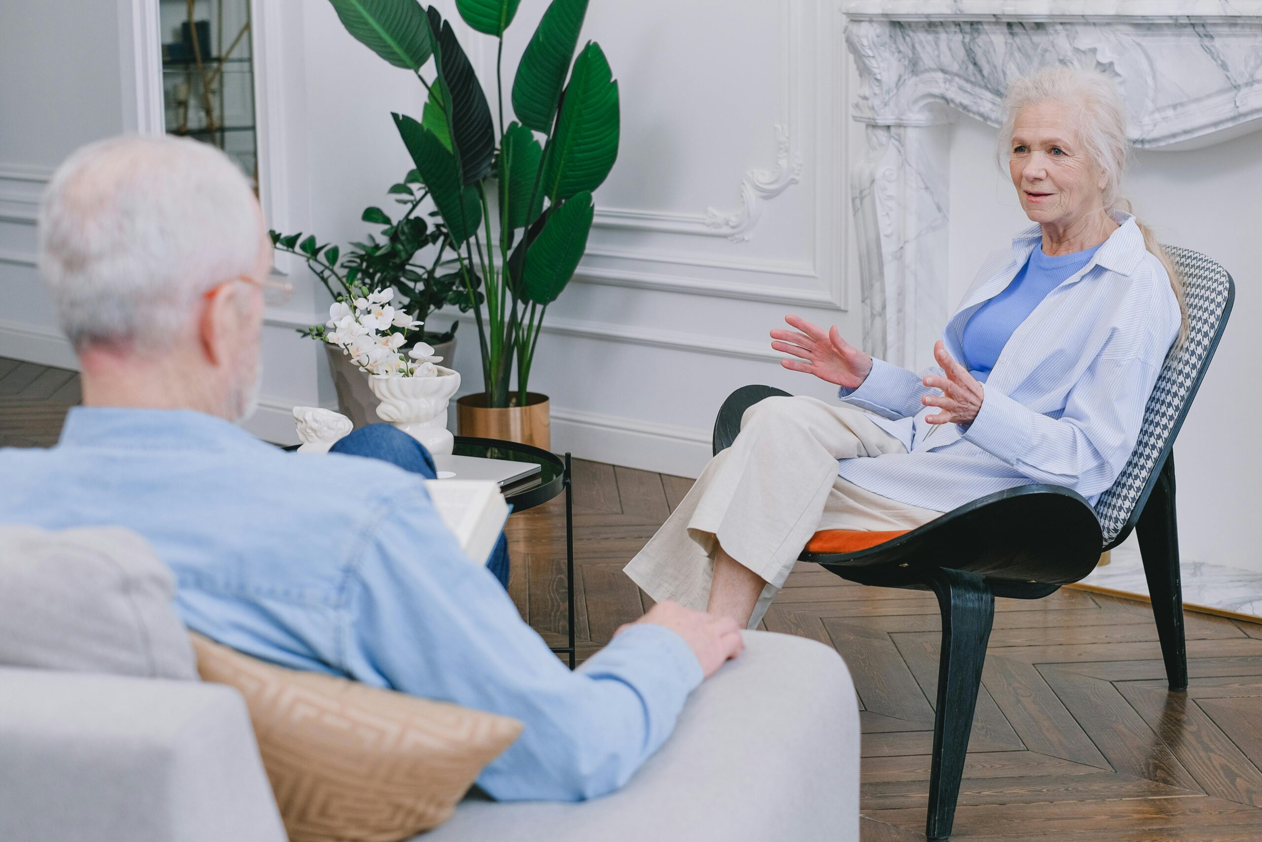 Elderly couple discussing in a stylish living room with plants.